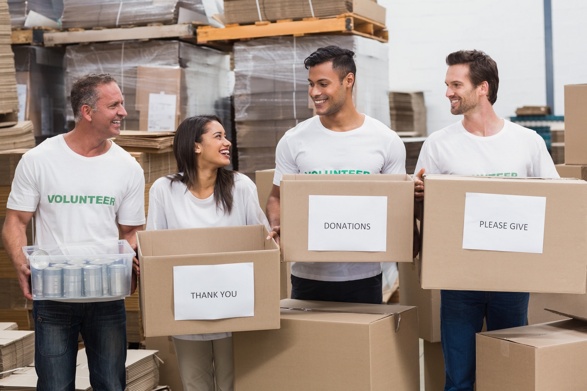 Happy Team of Volunteers Holding Donations Boxes in a Large Warehouse